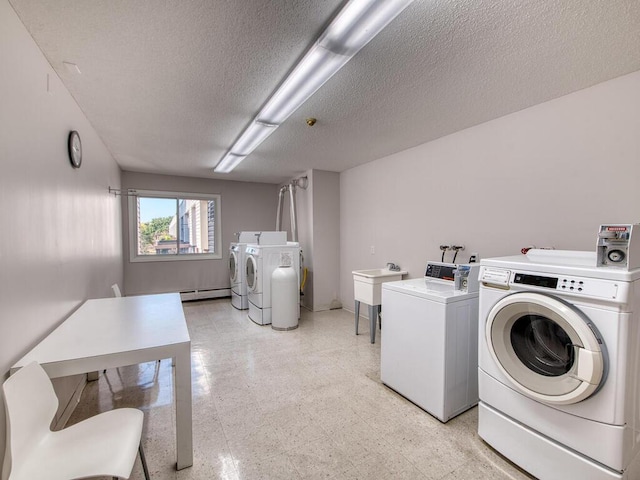 laundry room featuring washing machine and clothes dryer, a baseboard radiator, sink, and a textured ceiling