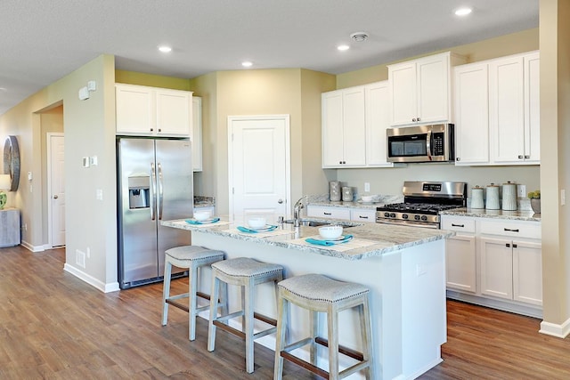 kitchen with white cabinetry, stainless steel appliances, a center island with sink, and sink