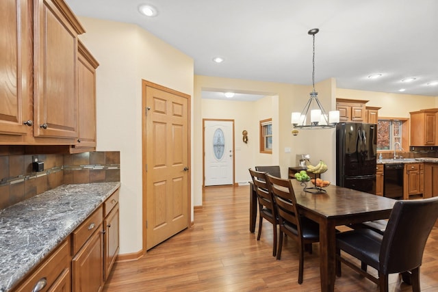 kitchen with decorative backsplash, sink, black appliances, light hardwood / wood-style floors, and hanging light fixtures