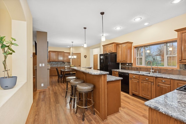 kitchen with a center island, backsplash, black appliances, sink, and decorative light fixtures