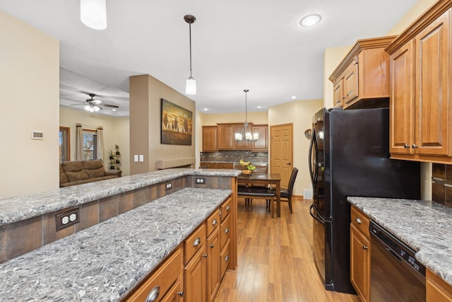 kitchen with tasteful backsplash, light hardwood / wood-style flooring, decorative light fixtures, black appliances, and ceiling fan with notable chandelier