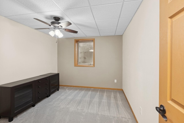 carpeted spare room with a drop ceiling and ceiling fan