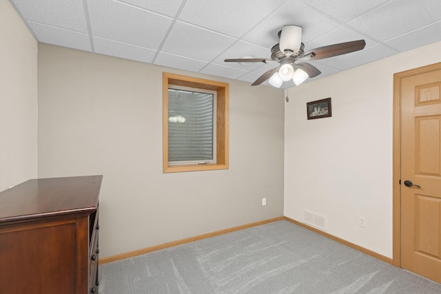 carpeted spare room featuring a drop ceiling and ceiling fan