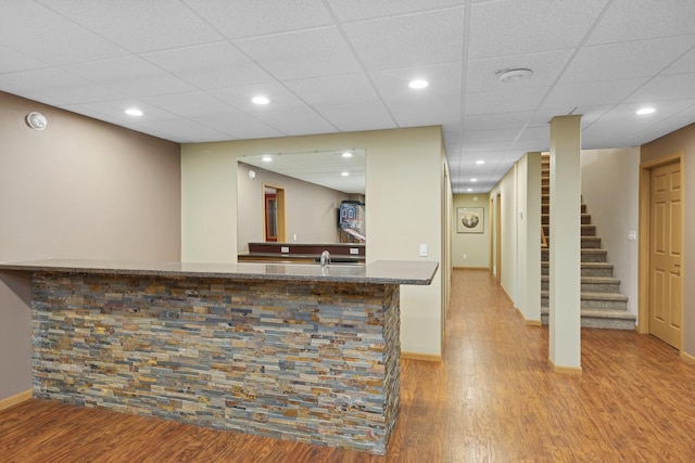 bar featuring a paneled ceiling and hardwood / wood-style flooring