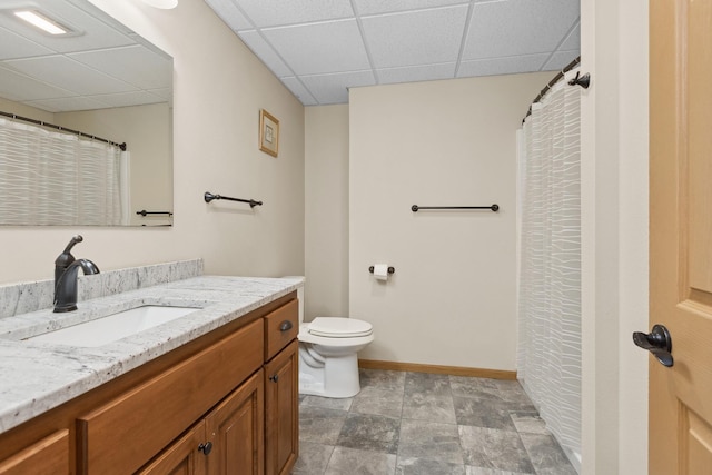 bathroom featuring vanity, toilet, and a drop ceiling