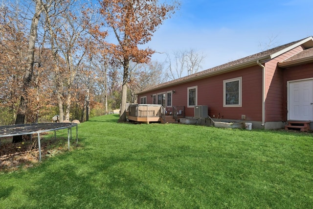 view of yard featuring a wooden deck, central AC unit, and a trampoline