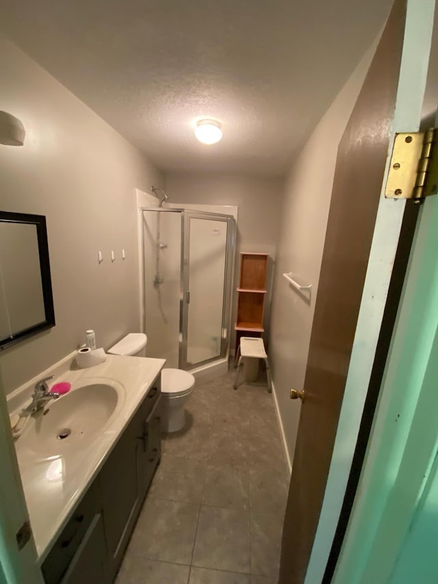 bathroom featuring vanity, tile patterned floors, toilet, a textured ceiling, and walk in shower