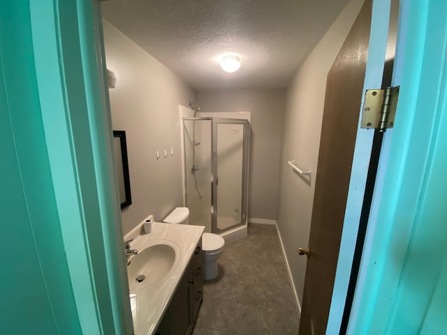 bathroom with tile patterned floors, walk in shower, vanity, a textured ceiling, and toilet