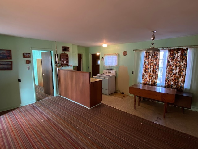 kitchen with washer / dryer, decorative light fixtures, and dark carpet