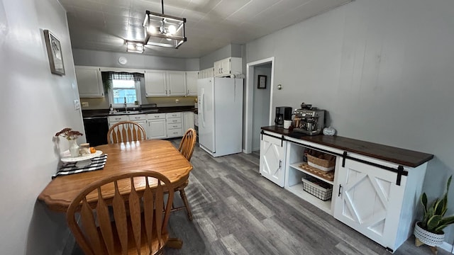 kitchen with white cabinets, black dishwasher, white fridge with ice dispenser, a barn door, and dark hardwood / wood-style floors