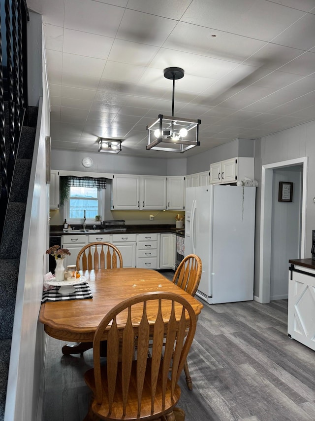 kitchen with white cabinets, hanging light fixtures, hardwood / wood-style flooring, and white fridge with ice dispenser