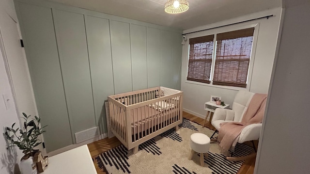 bedroom with a nursery area and wood-type flooring