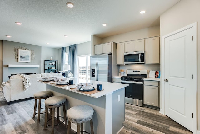 kitchen with a kitchen bar, gray cabinets, dark hardwood / wood-style floors, and appliances with stainless steel finishes