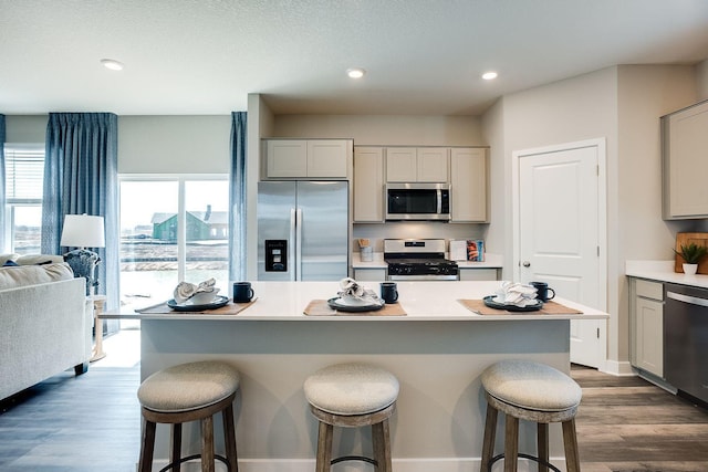 kitchen with stainless steel appliances, hardwood / wood-style flooring, a kitchen bar, and a kitchen island