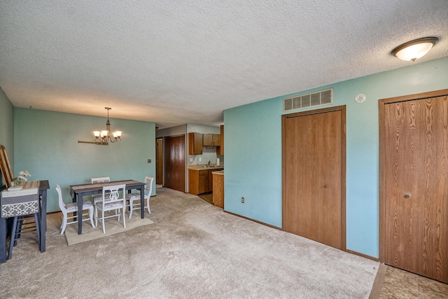 dining space with light colored carpet, a textured ceiling, and an inviting chandelier