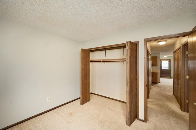 unfurnished bedroom with light colored carpet, a closet, and a textured ceiling