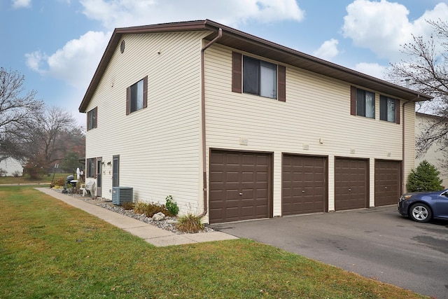 view of side of property with a garage, a yard, and central AC unit