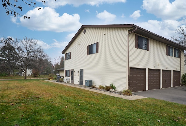 view of side of property with a garage, a lawn, and central AC