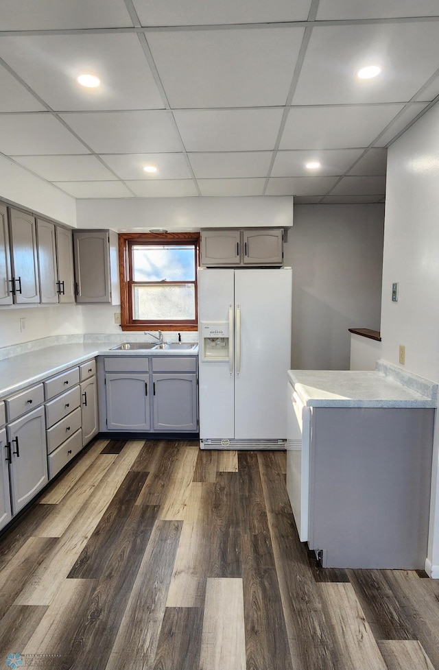 kitchen with white fridge with ice dispenser, sink, dark wood-type flooring, and gray cabinetry