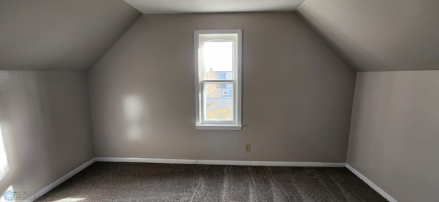 bonus room featuring lofted ceiling, plenty of natural light, and dark colored carpet