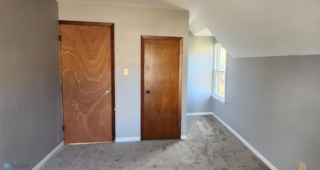 unfurnished bedroom featuring lofted ceiling and carpet floors