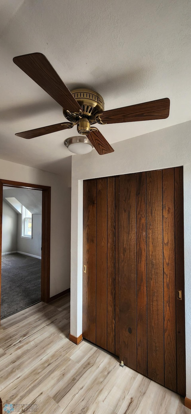 unfurnished bedroom with light hardwood / wood-style flooring, a textured ceiling, and ceiling fan