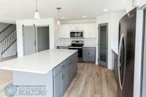 8447 61st St S, Horace, ND 58047 - kitchen featuring stainless steel appliances, light wood-style flooring, tasteful backsplash, light countertops, and hanging light fixtures