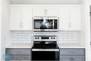 8447 61st St S, Horace, ND 58047 - kitchen with appliances with stainless steel finishes, light countertops, gray cabinetry, and backsplash