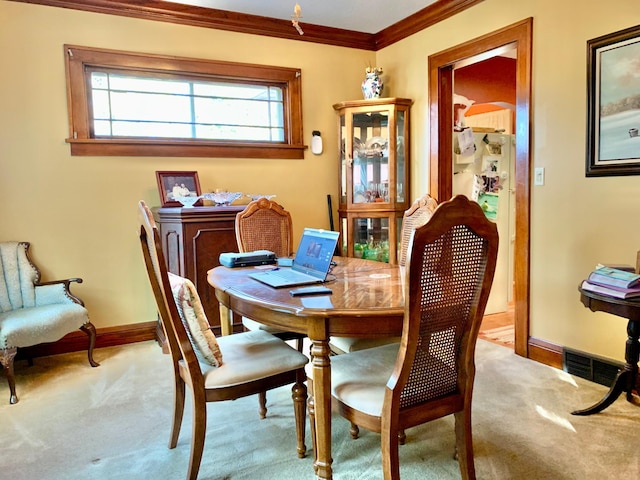 dining room featuring crown molding and light carpet