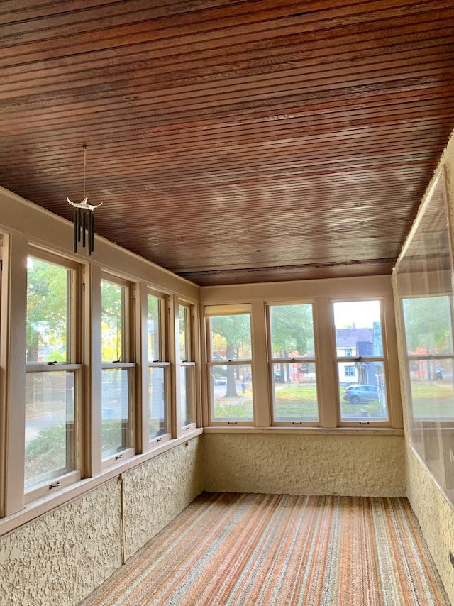 unfurnished sunroom featuring wood ceiling and a wealth of natural light