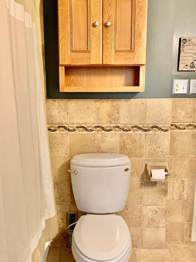 bathroom with toilet and tile walls