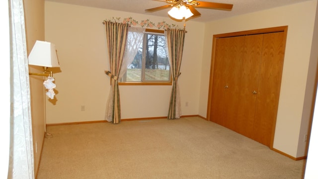 unfurnished bedroom featuring ceiling fan, light carpet, and a closet