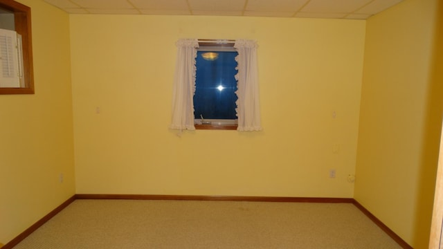 carpeted empty room with a paneled ceiling