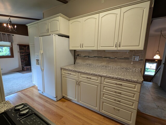 kitchen with light hardwood / wood-style flooring, white refrigerator with ice dispenser, pendant lighting, an inviting chandelier, and tasteful backsplash