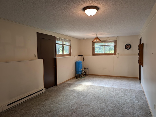 basement featuring a baseboard radiator, a textured ceiling, and plenty of natural light