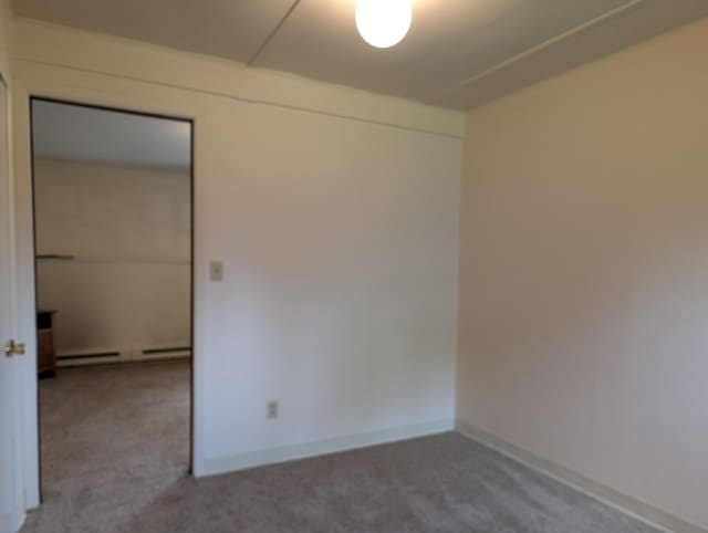 carpeted empty room featuring baseboard heating