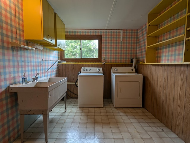 laundry area with cabinets, wooden walls, and separate washer and dryer