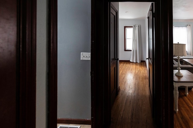 hallway with visible vents, hardwood / wood-style flooring, and baseboards