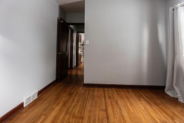 hallway featuring dark wood-type flooring, visible vents, and baseboards