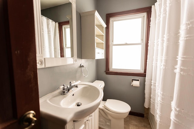 full bathroom featuring toilet, vanity, a wealth of natural light, and tile patterned floors