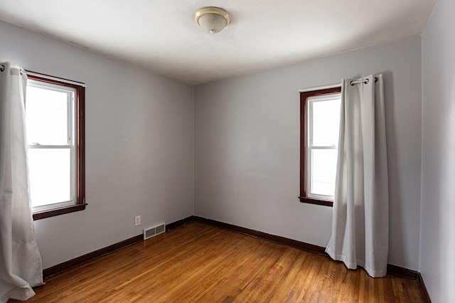 spare room with light wood-style floors, visible vents, and baseboards