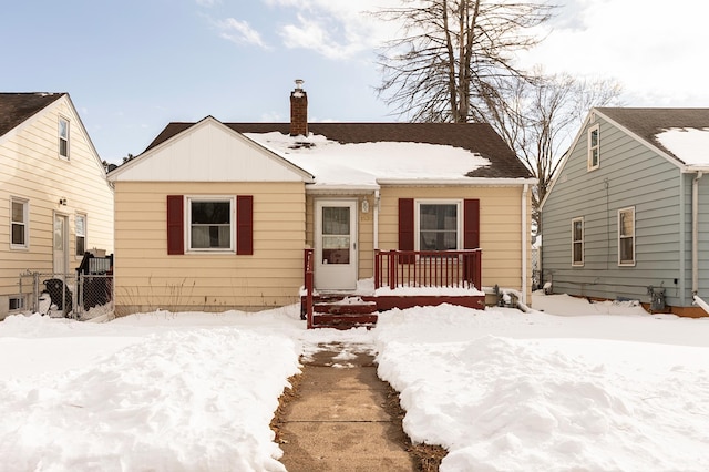 bungalow-style home with a chimney and fence