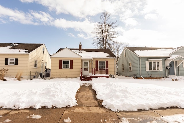 snow covered rear of property featuring a chimney