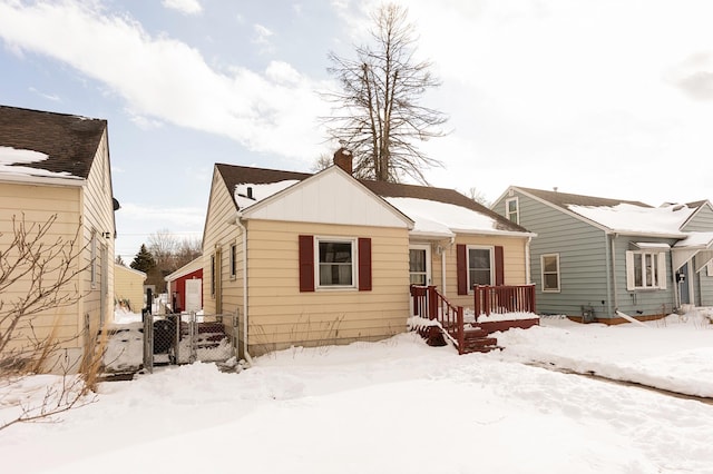 bungalow featuring board and batten siding, a chimney, and fence