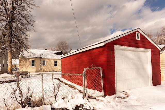 snow covered garage with a garage and fence