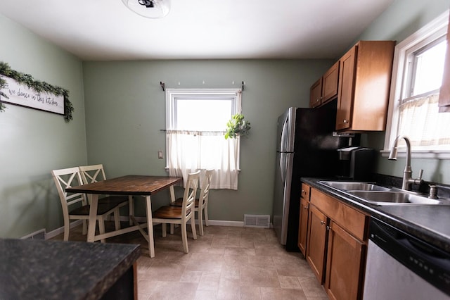 kitchen featuring a sink, visible vents, brown cabinets, dishwasher, and dark countertops