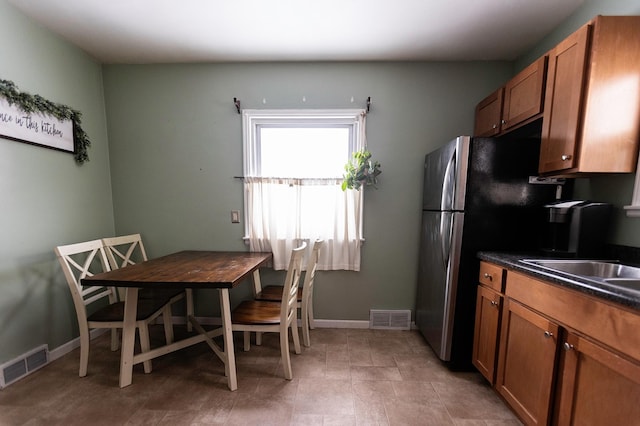 kitchen with brown cabinetry, dark countertops, visible vents, and baseboards