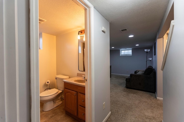 bathroom with a textured ceiling, toilet, recessed lighting, vanity, and visible vents