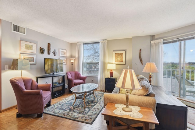 living room with light parquet floors, a healthy amount of sunlight, and a textured ceiling