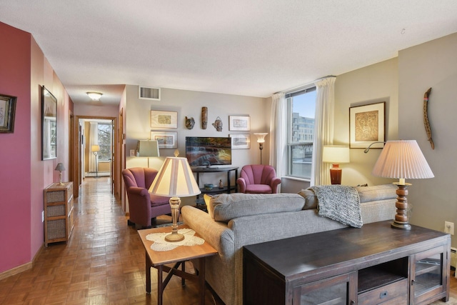 living room featuring a textured ceiling, parquet flooring, and a healthy amount of sunlight